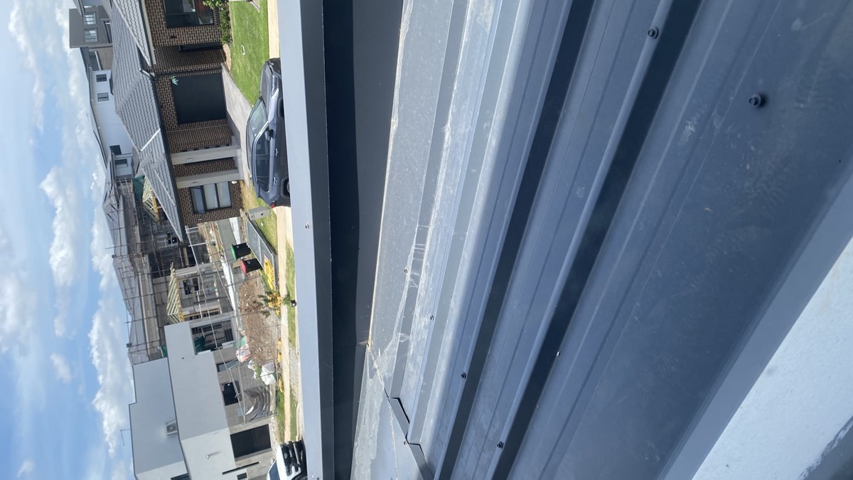 Parapet capping fixed from the top, recorded during a handover inspection in Austral